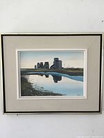Front view of framed painting showing grain elevators and water reflection