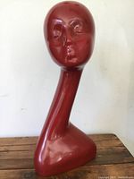 Front view showing facial features and elongated neck of the red mannequin head.