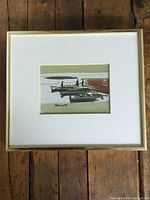 Full view of framed watercolour painting showing the artwork, matting, frame, and wooden floor background.