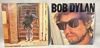 Front covers of two Bob Dylan vinyl albums 'Street Legal' and 'Infidels' side by side showing album artwork and condition.