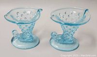 Front angle showing both candle holders with hobnail patterned bodies and cornucopia shape in blue opalescent glass.