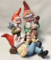 Set of three vintage garden gnomes grouped together, showing their relative sizes and colorful details including red hats and painted facial features.