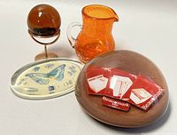 Paperweight, orange creamer, lacquer ball stand, and butterfly dish arranged on white surface.