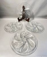 Four clear glass Arcoroc oyster plates with six oyster-shaped sections each, arranged three on the table and one on a display stand.