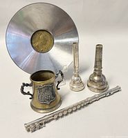 Group photo showing the miniature cup, bard decorated bowl, two trumpet mouthpieces, and partial miniature flute from side angle