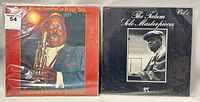 Two vinyl LP albums: one featuring Buddy Tate in a blue suit playing saxophone against a red background, the other featuring a black and white photo of Tatum on a black background with white text.