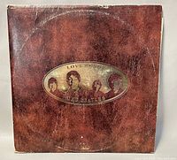Front cover showing textured brown background with gold emblem of The Beatles silhouettes and title