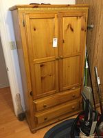 Front view of natural pine armoire with paneled doors and two drawers at base