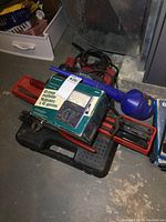 Overview photo showing the multimeter box, battery charger, and pry bars on top of the socket set case.