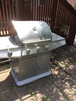 Front view of entire grill on patio showing hood, control panel, cabinet base