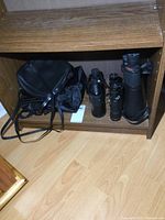 Three pairs of binoculars and two cases arranged on a wooden shelf