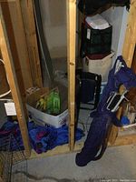 View of camping gear in unfinished basement wall section including coolers, cushion, backpack, and folded items