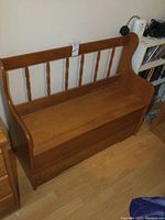 Front view of maple storage bench showing spindle backrest and hinged seat closed