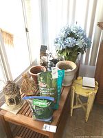 Overview of planters, potting mix, birdhouse, and small vintage table near sliding glass door.
