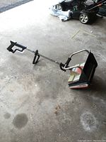 Full side view of the electric snow thrower showing handle, shaft, and main body.