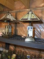 Pair of stained glass lamps on gray metal shelving against insulated wall