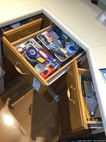 View of three open wooden drawers containing various hand tools, tape measures, electrical tape, and hardware items.
