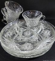 Four stacked glass cups placed on top of four glass plates showing starburst and floral patterning