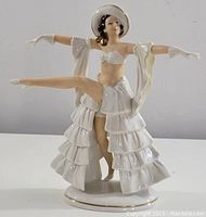 Front view showing the outstretched arms and detailed ruffled skirt.