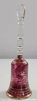 Full view of the glass bell showing clear handle and purple body with gold detailing.