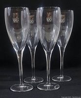 Four clear crystal champagne flutes standing upright showing their shape and stem design.