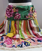 Close-up of tiered apron showing floral patterned waistband and multicolor striped middle tier with floral bottom tier trimmed with lace.