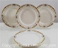 Four white salad plates with gold decorative urn motifs and geometric borders, displayed on stands and flat