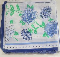 Tablecloth folded showing blue floral pattern and part of the scalloped blue border.