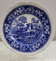 Front view of a Spode Blue Tower porcelain dinner plate showing scenic blue tower, bridge, and landscape with floral patterned border on white plate with scalloped edge.