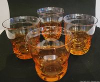 Four vintage curvy beverage glasses with golden ombre and iridescent finish arranged in a cluster viewed from above showing variation in shape.