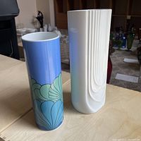 Two German vases side by side, one blue with painted shell design (Rosenthal) and one white with linear embossed design (Hutshenreuther).