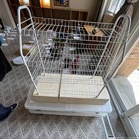 White metal 4-level shoe rack shown empty, placed on carpet, with boxes inside bottom section.