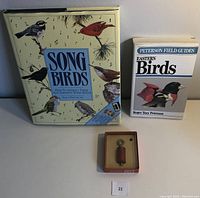 Lot items arranged on flat surface, showing two bird guide books and vintage Audubon bird call in box