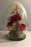 Front view of the glass domed display with red and yellow dried flowers and butterfly inside.