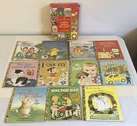 Set of 11 Little Golden Books with original red box upright at back; books arranged in front showing colorful children's storybook covers.