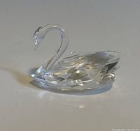 Clear crystal swan figurine viewed from side angle showing detailed wing facets and curved neck.