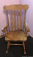 Full view of the wooden rocking chair showing backrest, seat, armrests, and rockers.