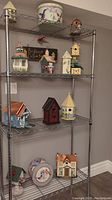 Photo of wire shelving unit displaying eleven wooden birdhouses and two round decorative boxes with bird designs.
