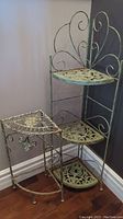 Photo of two metal corner shelves showing full view with ornate scroll and cutout designs