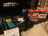 Shelf containing Dremel Model 9000 rotary saw in black plastic carrying case, Remington Power Hammer box, and a partial box of Remington power fasteners.