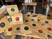 Overview photo showing approximately 30 vintage 78 RPM records in original sleeves from multiple labels including Columbia, Bluebird, Victor, Decca.