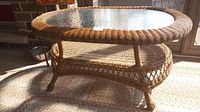 Front view of oval wicker coffee table with glass top and lower shelf