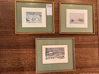 Set of three vintage framed Canadian prints displayed on a wooden floor, showing general condition and style of frames and mats.