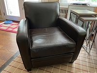 Front view of brown leather lounge chair showing removable seat cushion and wooden block feet