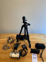 Entire lot including tripod, Sony camcorder, Nikon camera, carrying case, AC adapter and USB cable on table