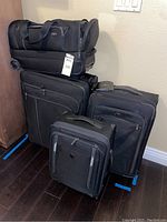 Four-piece luggage set featuring a duffle bag with wheels on top and three suitcases below, all black with Victorinox Swiss Army branding.