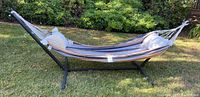 Metal hammock stand with hammock and pillows set up outside on grass