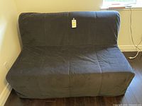 Photo of dark gray fabric sofa in upright seating mode with visible tag on backrest