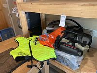 Kayak accessories including manual pump, dry bag, life jacket, waterproof pouch and oars displayed on shelf