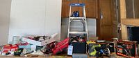Full view of the lot on a table including ladder, power tools, toolboxes, and hardware items scattered and organized.